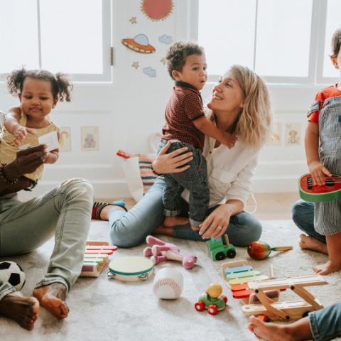 foto con una donna, seduta in mezzo a giochi sparsi sul pavimento, che stringe a se un bambino