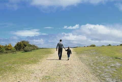 immagine con un uomo che conduce per mano un bambino lungo una strada