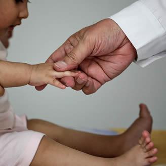 immagine con la mano di un medico che tiene quella di un bambino 