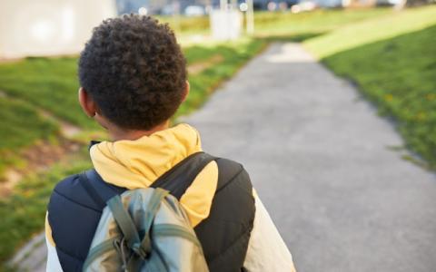 Bambino di spalle che pwercorre una strada